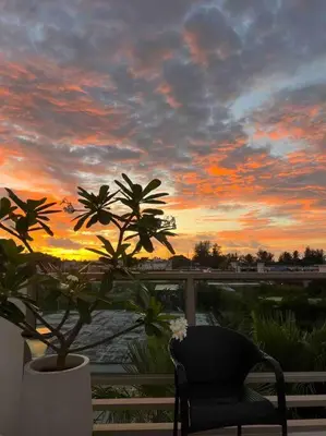 a chair and a plant on a balcony with a sunset at The Regent Kamala Penthouse with private pool in Kamala Beach