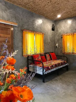 a bed with red pillows in a room with flowers at Big hug home-Forest House in Ban Takhrai