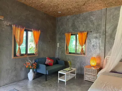 a living room with a couch and two windows at Big hug home-Forest House in Ban Takhrai