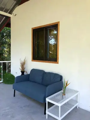 a blue couch in a living room with a window at Big hug home-Forest House in Ban Takhrai
