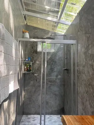 a shower with a glass door in a bathroom at Big hug home-Forest House in Ban Takhrai