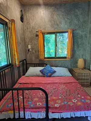 a bedroom with a bed with a red comforter and two windows at Big hug home-Forest House in Ban Takhrai