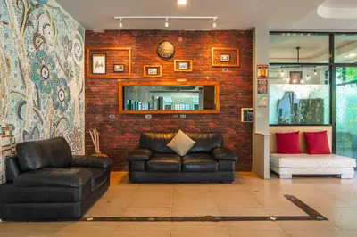 a living room with a leather couch and a mirror at Coco Retreat Phuket Resort and Spa - SHA Plus in Chalong