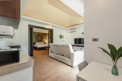 a living room with a couch and a kitchen at Coco Retreat Phuket Resort and Spa - SHA Plus in Chalong