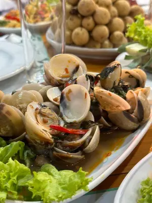 a plate of clams and vegetables on a table at BT hotel Kata Beach in Kata Beach