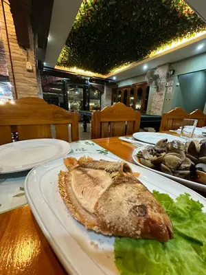 a fish on a plate on a table with lettuce at BT hotel Kata Beach in Kata Beach
