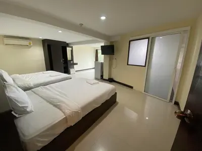 a bedroom with two beds and a television in it at The Elegant Patong in Patong Beach