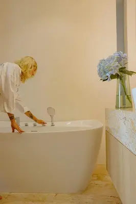 a woman is standing next to a bath tub at Elite Atoll Serviced Apartments Phuket in Rawai Beach