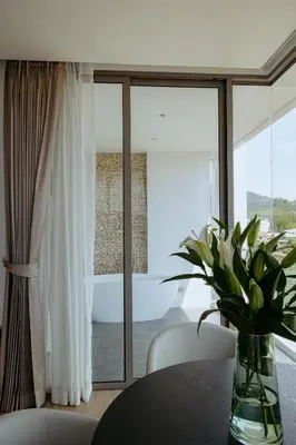 a dining room with a table and a window at Elite Atoll Serviced Apartments Phuket in Rawai Beach
