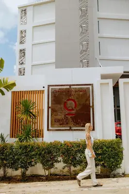 a woman walking down a street in front of a building at Elite Atoll Serviced Apartments Phuket in Rawai Beach