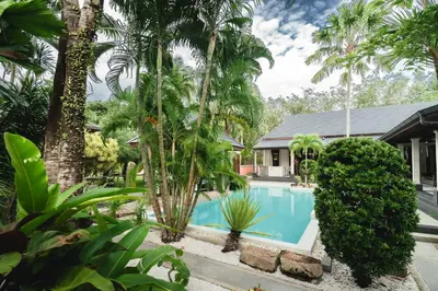 a swimming pool in front of a house with palm trees at Villa Banyak Luxury 4Br villa with nice terrace in Rawai Beach