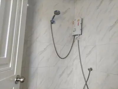 a shower with a shower head on a white tile wall at Heimat Garden Homestay in Ban Lo Pa Ret