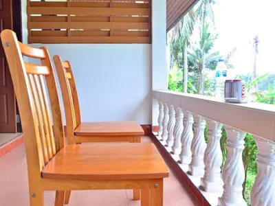 a wooden chair sitting on a balcony with a window at Heimat Garden Homestay in Ban Lo Pa Ret