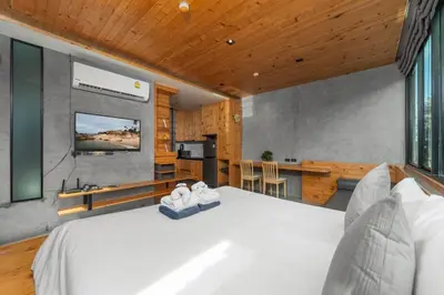a bedroom with a large white bed and a kitchen at Modern studio at Relife 2 min to Nai Harn beach in Rawai Beach