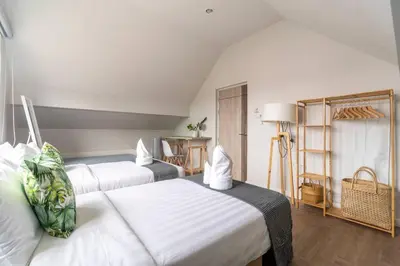 a hotel room with two beds and a table at Naka Cozy House in Phuket City in Ban Rangeng