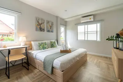 a bedroom with a bed and a desk and two windows at Naka Cozy House in Phuket City in Ban Rangeng