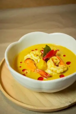 a white bowl of soup on a wooden plate at Kamala Beach Residence in Kamala Beach