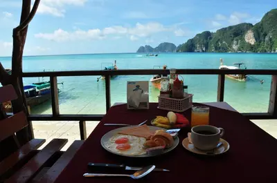 a table with a plate of eggs and a view of the ocean at Phi Phi Rimlay Resort in Phi Phi Don