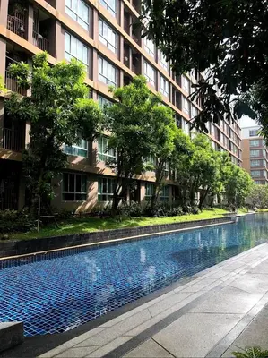 a swimming pool in front of a tall building at Cozy and delightful room with pool view in Kathu
