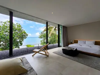 a bedroom with a bed and a view of the ocean at Luxury Beachfront AMANA Villa 4 Br at Ta-Ke Residence A in Phuket Town