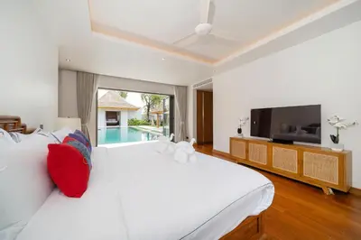 a bedroom with a large white bed and a tv at Spacious Mansion 4BR Villa Anchan V20 with 15m Private Pool in Gated Residence in Bang Tao Beach