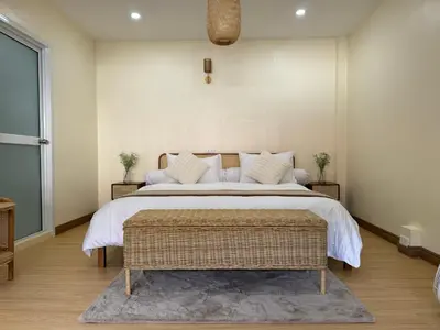 a bedroom with a large bed with white sheets and a rug at L’Oasis Nanai in Patong Beach