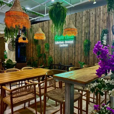 a restaurant with wooden tables and chairs and flowers at L’Oasis Nanai in Patong Beach