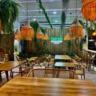 a restaurant with wooden tables and chairs and plants at L’Oasis Nanai in Patong Beach