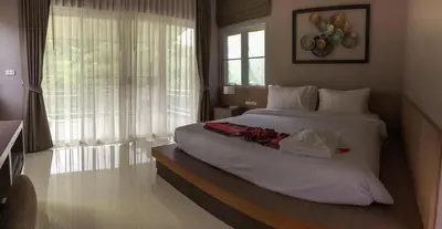 a bedroom with a large white bed and a window at Bangnu Greenery Resort in Takua Thung