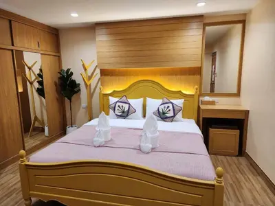 a bedroom with a large bed with a wooden headboard at Alaita Hostel Patong in Patong Beach