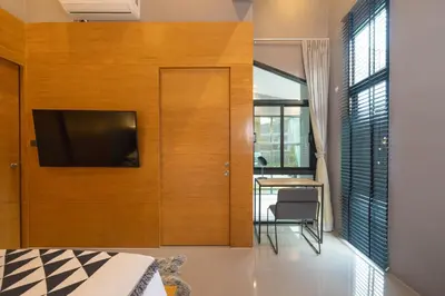 a bedroom with a flat screen tv on a wooden wall at Serene Wallaya Villa Harmony in Ban Pak Lak