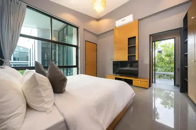 a bedroom with a large white bed and a television at Serene Wallaya Villa Harmony in Ban Pak Lak