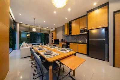 a kitchen and living room with a large wooden table at Serene Wallaya Villa Harmony in Ban Pak Lak