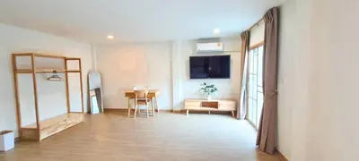 a living room with a table and a television on the wall at 48 House in Patong Beach