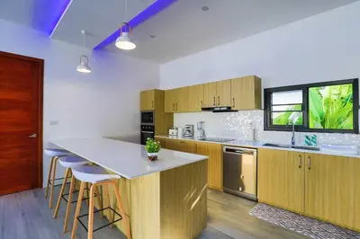 a kitchen with wooden cabinets and a island with bar stools at Sweet Luxury by G Estate Phuket in Ban Saiyuan (1)