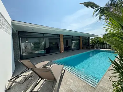 a swimming pool with two chairs and a house at Sweet Luxury by G Estate Phuket in Ban Saiyuan (1)