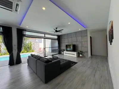 a living room with a black couch and a tv at Sweet Luxury by G Estate Phuket in Ban Saiyuan (1)