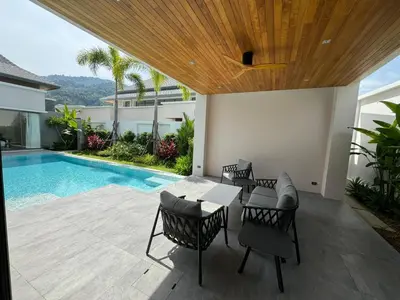 a patio with a table and chairs next to a swimming pool at Luxury Breeze Villa with private pool & maid in Bang Tao Beach