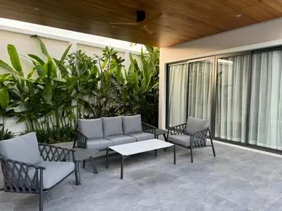a patio with chairs and a couch and a table at Luxury Breeze Villa with private pool & maid in Bang Tao Beach