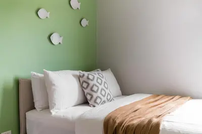 a bed with white pillows and a green wall at Great Hill Tropic View Pool Gym Naiyang in Nai Yang Beach