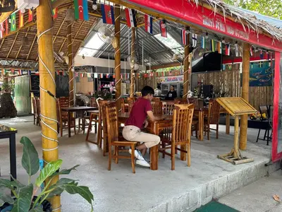 a man sitting at a table in a restaurant at Great Hill Tropic View Pool Gym Naiyang in Nai Yang Beach