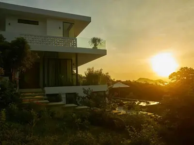 a building with the sunset in the background at Casa Alma by Elite Havens in Nai Harn Beach