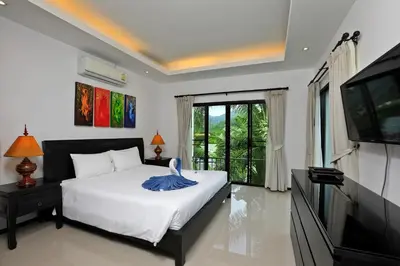 a bedroom with a bed and a flat screen tv at Thaimond Residence by TropicLook Walkable distance to Naiharn beach in Nai Harn Beach