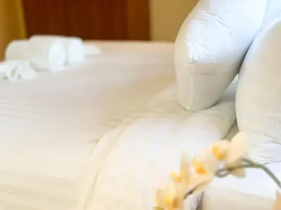 a bed with white sheets and flowers on it at Botanic Boutique Hotel Surin Beach in Bang Tao Beach