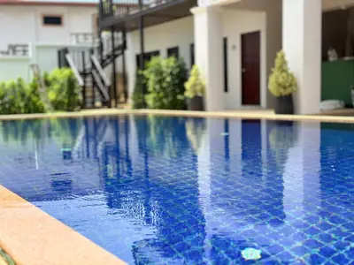 a swimming pool with blue water in front of a house at Botanic Boutique Hotel Surin Beach in Bang Tao Beach