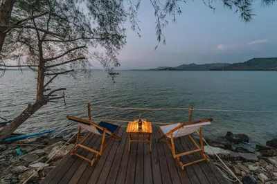 a table and two chairs sitting on a dock on the water at Sea Sand See Sky Beach Front Resort in Phuket Town