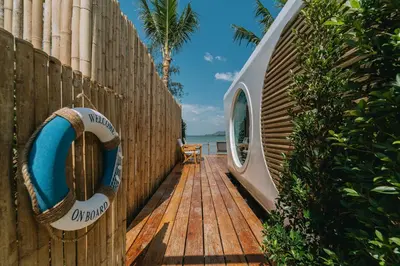 a wooden deck with a surfboard on a fence at Sea Sand See Sky Beach Front Resort in Phuket Town