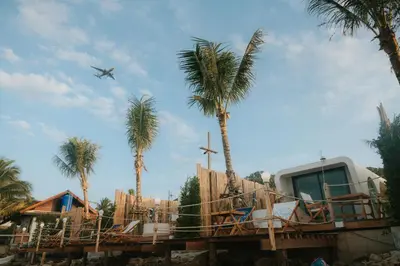 an airplane is flying over a house with palm trees at Sea Sand See Sky Beach Front Resort in Phuket Town