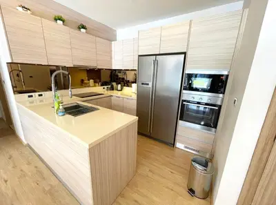 a kitchen with a stainless steel refrigerator and wooden cabinets at Baan Mai Khao 3 Br in Phuket Town