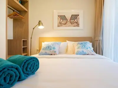a bedroom with a white bed with two chairs at 2 спальни Апартаменты на Бангтао 600 метров от моря in Bang Tao Beach